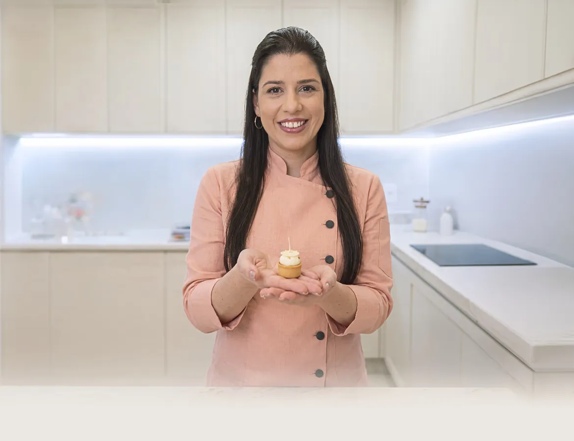 Natália Canezin na cozinha, segurando uma tartelette nas mãos